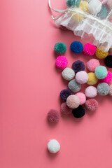 colourful yarn and wool pompoms for hobbies crafts and knitting on pink background 