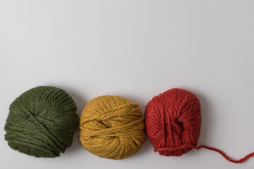 knitting background - balls of wool in natural earthy shades on a white background with copy space 