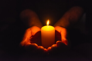 Burning candle in a mans hand religion concept.Candle in hands on a dark background.