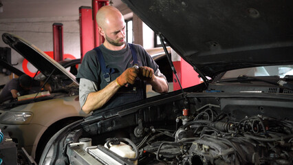 Naklejka na ściany i meble Auto mechanic repairs SUV engine. auto repair station. automobile