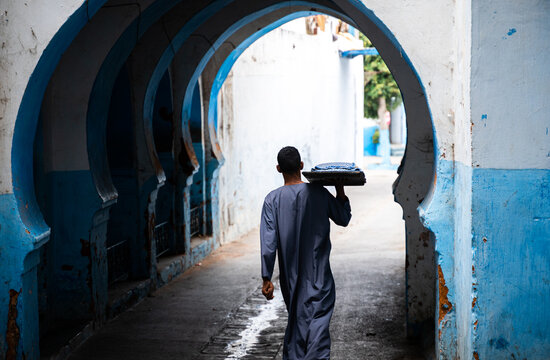 Hombre árabe portando comida diaria pasando por arco musulmán .