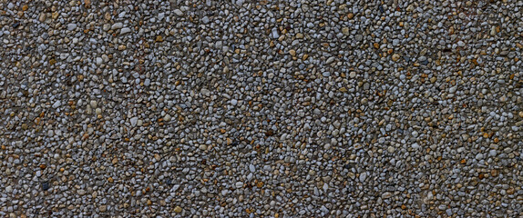 Panorama of small pebbles in concrete wall for background