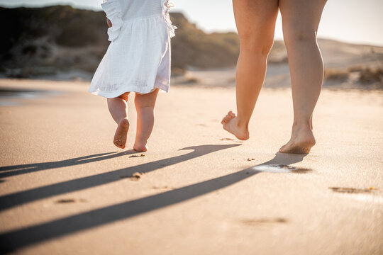 Madre e hija caminando por la playa. 