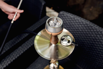 Hookah bowl with tobacco, heating device and coconut coal in hookah lounge.