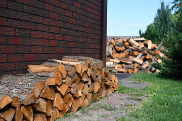 Pile of wood stacked at red brick wall. Selective focus.