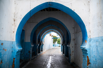 Fototapeta na wymiar Callejuela de Larache en Marruecos de arcos azules y blancos.