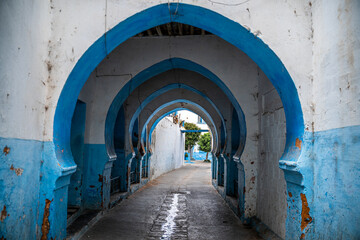 Callejuela de Larache en Marruecos de arcos azules y blancos. - obrazy, fototapety, plakaty
