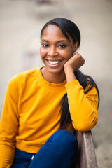 Happy black woman sitting outdoors on bench