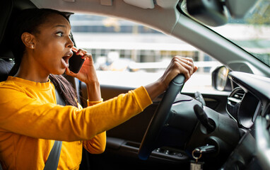 Shocked woman talking on mobile phone while driving car