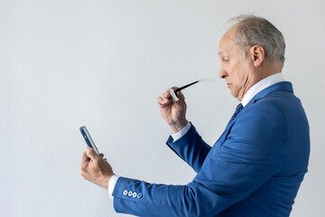 Portrait of mature businessman holding mobile phone and glasses. Senior manager wearing formalwear reading message on smartphone through eyeglasses in surprise. Mobile technology concept