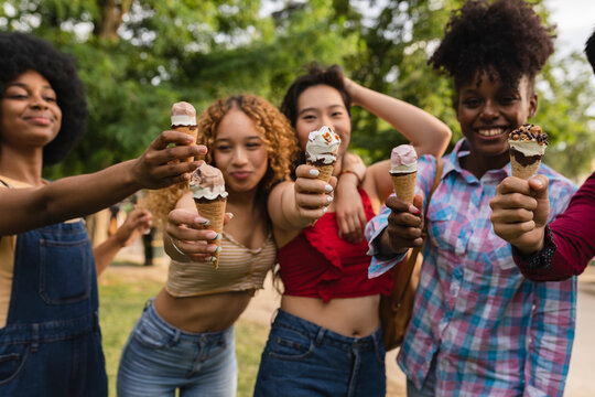 Group of multi-ethnic friends eating ice cream in the summer together having fun - focus on ice cream -