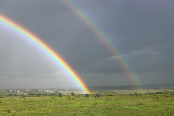 Bright double rainbow with dark rain clouds in the background