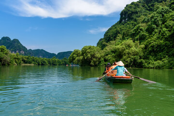 Tourists sitting on rowing boats enjoy the beautiful scenery of rivers and mountains in Trang An,...