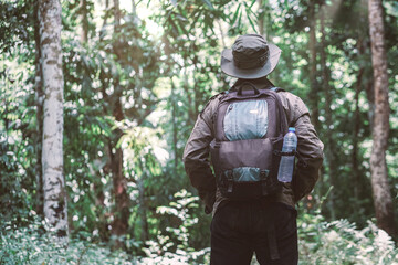 Fototapeta premium A hiking traveler standing with a backpack and a hat, traveller, hipster looking in the woods. Concept of adventures traveling