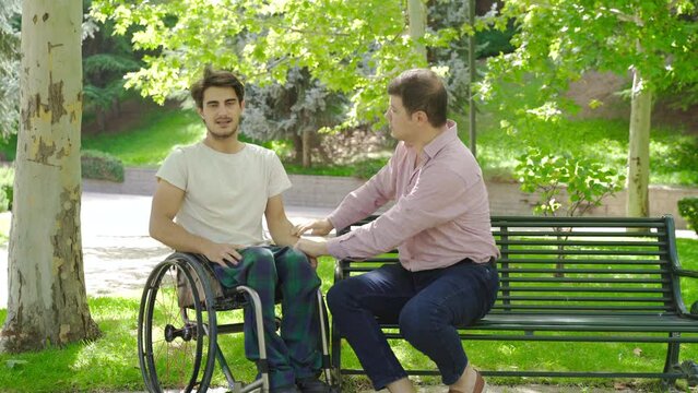 Frustrated disabled young man.
Outside, the disabled young man is in a nervous state and the man sitting next to him is calming him down.
