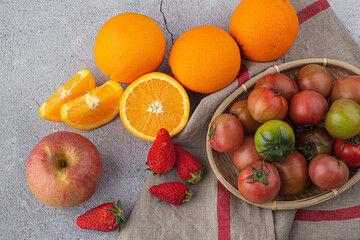 orange, tomatoes, apple, strawberry on a gary background