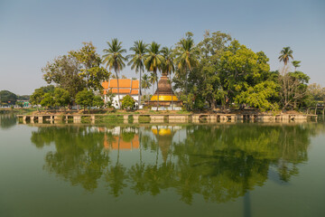 Obraz premium Landscape of the Wat Traphang Thong temple reflected in the water of the surrounding pond, at the Sukhothai Historical Park, Thailand