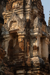 Fototapeta premium Decorative elements and reliefs in Wat Mahathat temple and pagodas of Thai style architecture and trees, in Sukhothai Historical Park at sunset