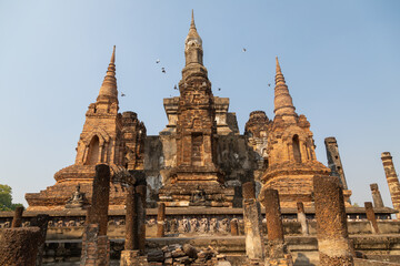 Fototapeta premium Wat Mahathat temple and pagodas of Thai style architecture and trees, in Sukhothai Historical Park at sunset