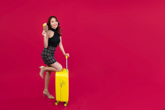 Beautiful Asian girl holding passport and credit card and yellow suitcase in red background scene. Summer travel concept, opening the country and international travel
