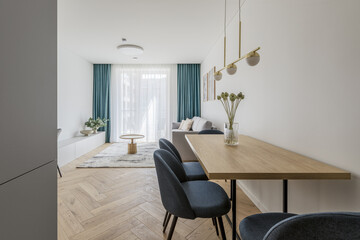 Modern minimalist kitchen and dining room interior design  with wooden furniture, oak floor. blue chairs.  Aesthetic simple interior design concept.