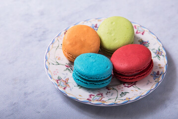 Macaroon cakes on a dessert saucer on a grey background