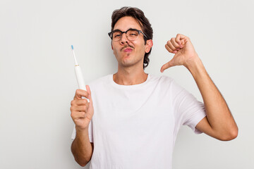 Young hispanic man holding electric toothbrush isolated on white background feels proud and self...