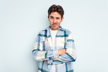 Young hispanic man isolated on blue background unhappy looking in camera with sarcastic expression.