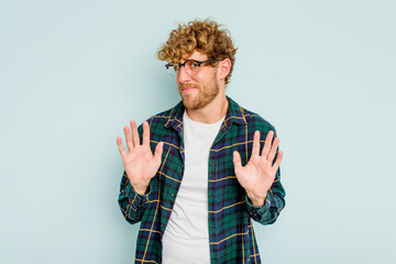 Young caucasian man isolated on blue background rejecting someone showing a gesture of disgust.
