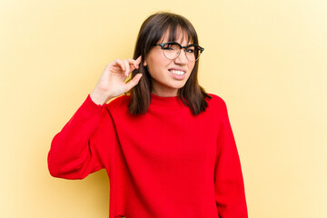 Young caucasian woman isolated on yellow background covering ears with fingers, stressed and desperate by a loudly ambient.