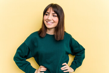 Young caucasian woman isolated on yellow background confident keeping hands on hips.