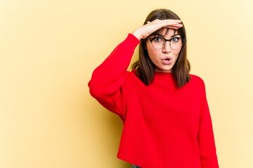 Young caucasian woman isolated on yellow background looking far away keeping hand on forehead.