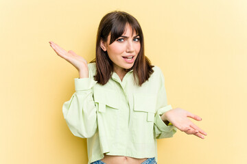 Young caucasian woman isolated on yellow background confused and doubtful shrugging shoulders to hold a copy space.