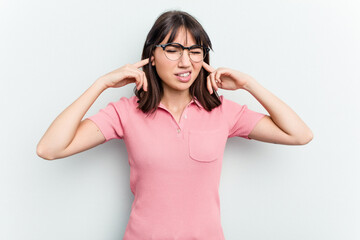Young caucasian woman isolated on white background covering ears with fingers, stressed and desperate by a loudly ambient.