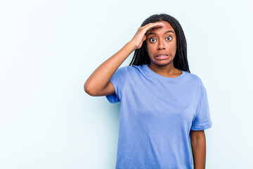 Young African American woman with braids hair isolated on blue background shouts loud, keeps eyes opened and hands tense.