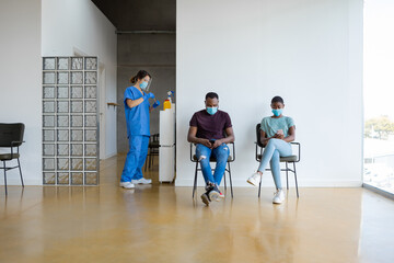 Man and woman in waiting room of a hospital, using mobile phone.