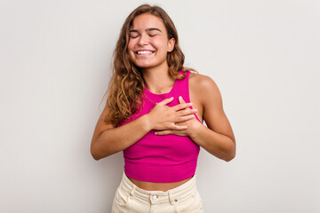 Young caucasian woman isolated on blue background laughing keeping hands on heart, concept of happiness.