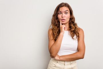 Obraz premium Young caucasian woman isolated on blue background looking sideways with doubtful and skeptical expression.