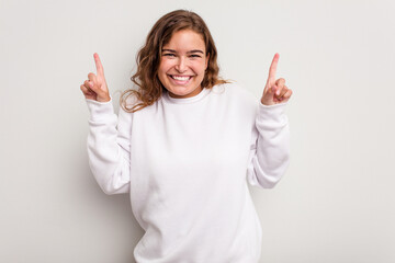 Young caucasian woman isolated on blue background indicates with both fore fingers up showing a blank space.