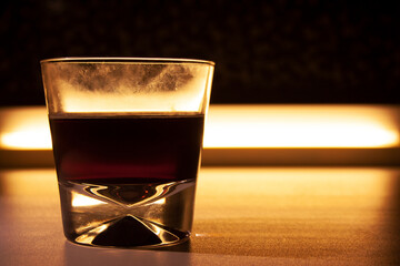 Glass of cocktail drink isolated on glowing background in dark