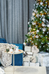 Interior of living room decorated for New Year and Christmas. Blue sofa and Christmas tree in lights