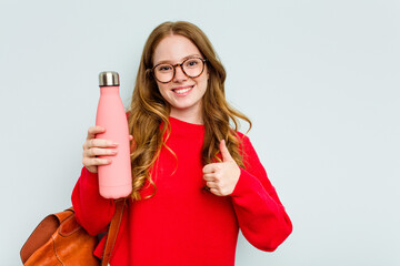 Young student woman holding a canteen isolated on blue background smiling and raising thumb up