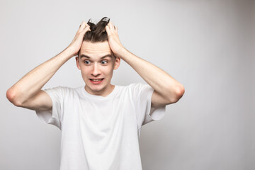 Confused young man holding his head studio shot on gray background