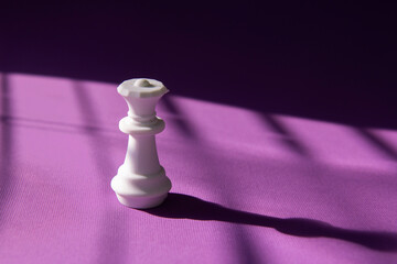 White chess queen on a purple background. Abstract background. Chess piece. Concept of leadership,...