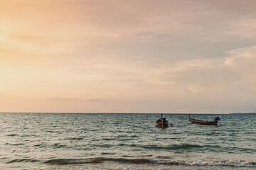 Sunset view of Mai Khao Beach in Phuket Thailand with two local long tail boats.