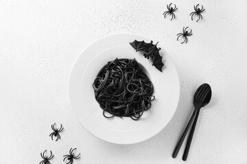 Halloween alternative creative Italian black pasta squid ink decorated funny spiders and bat on white background. View from above. Food concept.