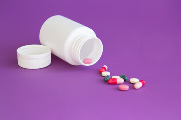 White bottle of vitamin tablets and capsules on a purple background. Dietary supplements