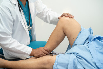 Asian doctor physiotherapist examining, massaging and treatment knee and leg of senior patient in...