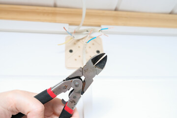 Electrician use of the stripper cutter tool to strip the end of the electrical wire when repairing and updating wiring in the home grid. Electric installation work