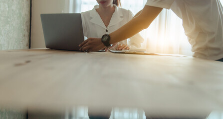 Fototapeta premium A businesswoman uses a computer and a graph to work on a wooden table. At dawn, summarize the company's profits with a successful graph. Review the quarterly reporting results using a business idea. 